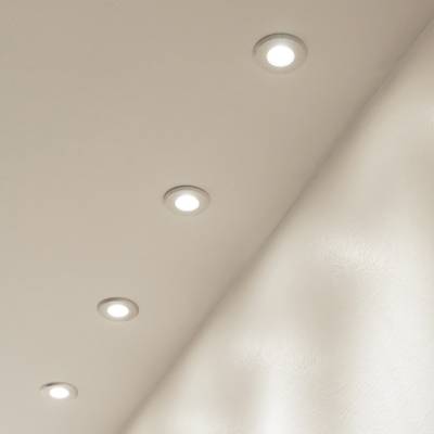 Plafond avec cinq lampes LED encastrées dans une rangée, émettant une lumière douce sur une surface beige. Idéal pour un éclairage moderne et économe en énergie.