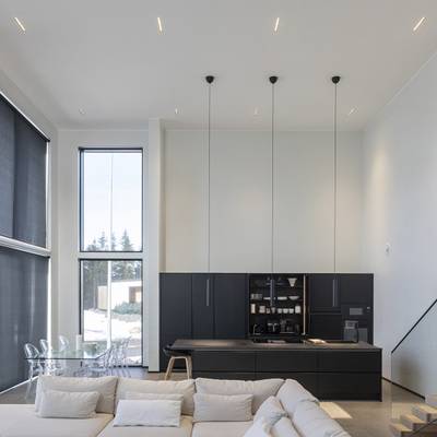 Éclairage de cuisine moderne avec des lampes suspendues, la lumière naturelle des grandes fenêtres, des LED d'ambiance et d'accentuation.