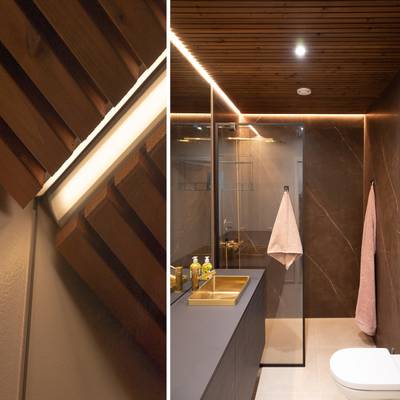 Salle de bains moderne avec un éclairage LED stylé, un plafond en bois, des accents lumineux doux et un miroir éclairé.
