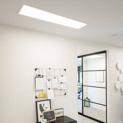 Les luminaires LED pour plafond de bureau éclairent un espace de travail moderne avec une cloison en verre et un tableau noir.