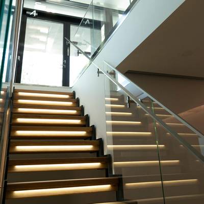 L'éclairage d'escalier illumine les escaliers en verre ; les lampes LED modernes renforcent l'atmosphère de l'intérieur, avec la lumière naturelle au-dessus.