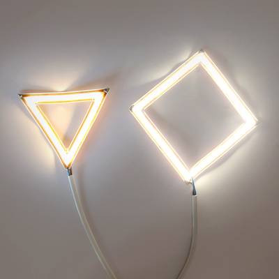 Gros plan d'une bande lumineuse à LED montrant le câblage avec des câbles rouges et noirs sur un fond blanc.