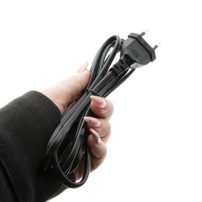 Gros plan d'une main tenant un fil électrique noir torsadé avec une fiche à deux broches, isolée sur fond blanc pour les solutions d'éclairage LED.