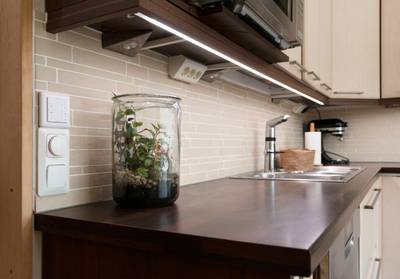 L'éclairage LED sous l'armoire illumine le plan de travail de la cuisine, qui abrite le terrarium, l'évier, la robinetterie et les appareils électroménagers.