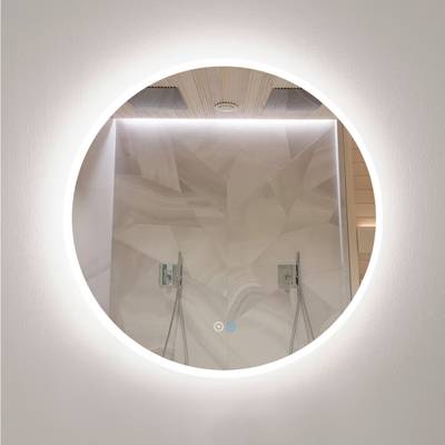 Un miroir de salle de bains circulaire rétroéclairé par LED met en valeur la douche moderne, les carreaux géométriques et les doubles luminaires.