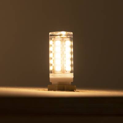 Une lampe LED chaleureuse, brillant sur un fond sombre, positionnée verticalement pour une diffusion optimale de la lumière et une efficacité énergétique. Parfaite pour les maisons écologiques.