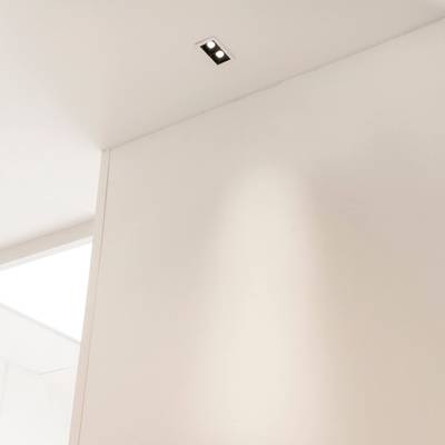 Une pièce minimaliste avec un plafond et des murs blancs et un élégant luminaire LED encastré rectangulaire pour un éclairage moderne.