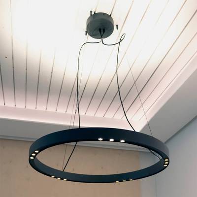 Élégant lustre LED rond à multiples lumières suspendu à un plafond blanc. Le câblage visible ajoute à l'atmosphère industrielle. Parfait pour les intérieurs modernes.