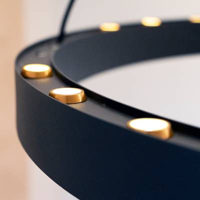 Gros plan sur un anneau lumineux circulaire noir à LED avec des lumières dorées régulièrement espacées, parfait pour la photographie et l'éclairage vidéo.