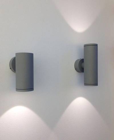 Les appliques LED cylindriques modernes diffusent une lumière douce vers le haut et vers le bas sur un mur blanc, créant une ambiance élégante dans un design d'éclairage contemporain.