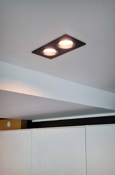 Plafond avec deux encastrés LED rectangulaires émettant une lumière chaude, vue partielle des armoires et de la poutre du dessous. Idéal pour l'éclairage d'une maison moderne.