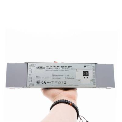 Gros plan d'une main tenant le variateur LED VaLO TRIAC-100W-24V avec affichage digital, qui améliore l'efficacité énergétique de l'éclairage LED.