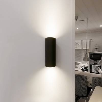 Applique LED cylindrique noire moderne pour éclairer le mur blanc de la salle à manger. Design intérieur moderne avec des luminaires à faible consommation d'énergie.