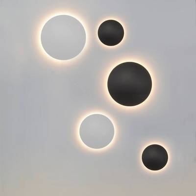 Cinq appliques rondes modernes, trois noires et deux blanches, diffusent une lumière chaude sur un fond clair. Un éclairage LED élégant pour les intérieurs contemporains.