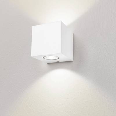 Cette applique minimaliste blanche cube éclaire un mur blanc doucement texturé avec une lumière ascendante et descendante. Parfaite pour un éclairage LED moderne.