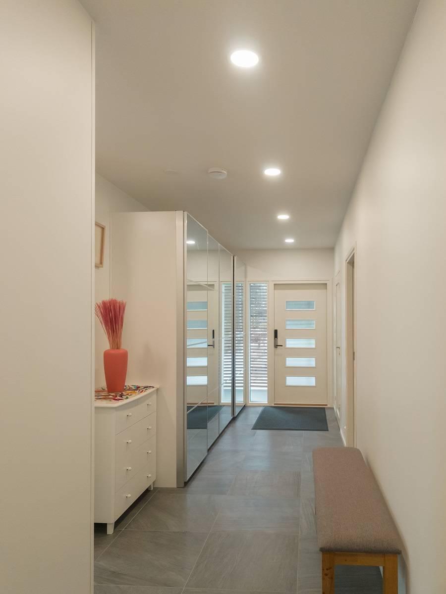 Le couloir lumineux est éclairé par de petites lampes rondes.