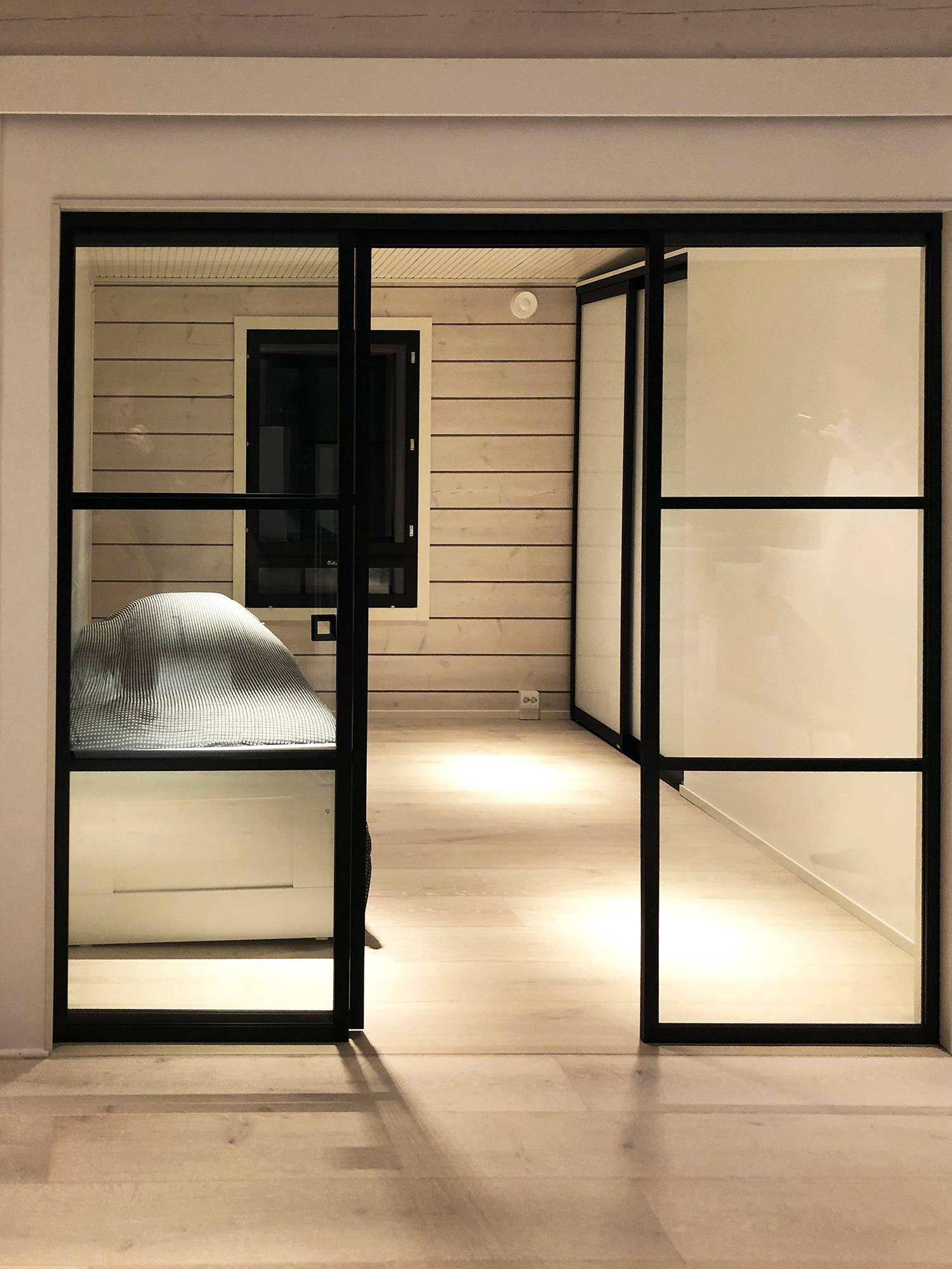 Lumière d\'ambiance dans la chambre à coucher réalisée avec des lampes linéaires à angle étroit qui créent des motifs lumineux clairs. Ledstore.fi