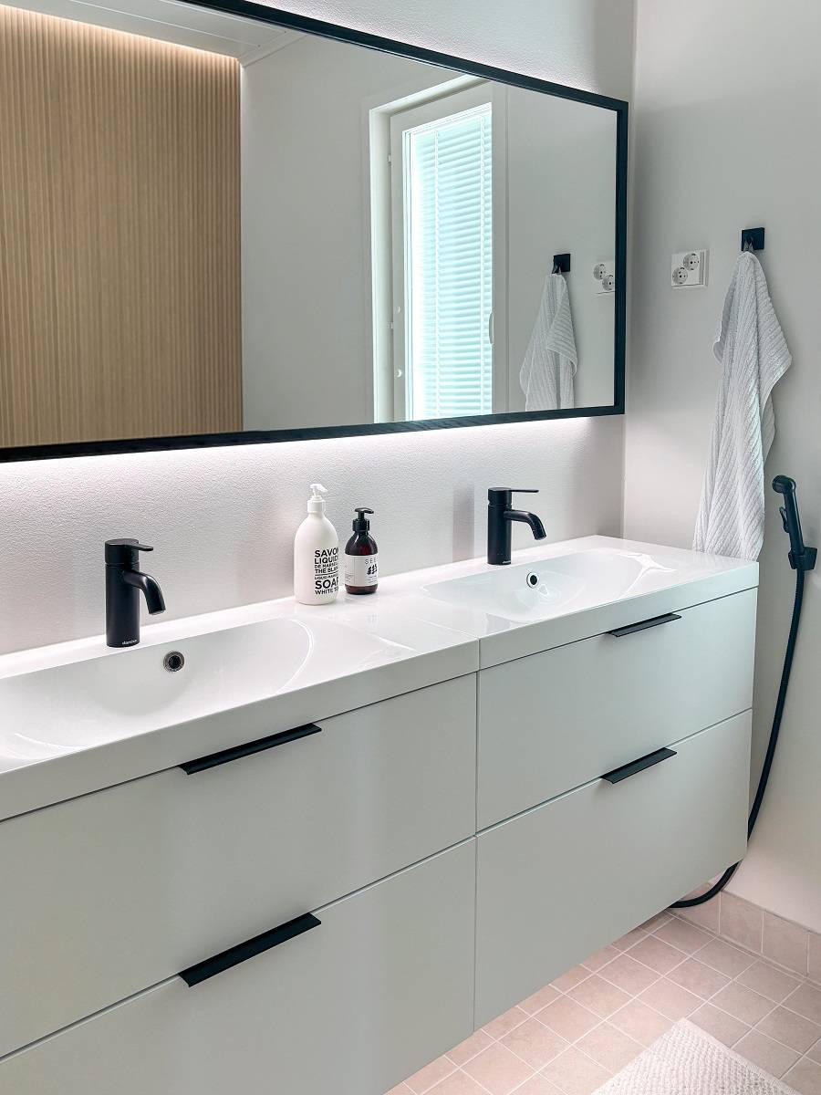 Un grand miroir lumineux éclaire une pièce en reflétant la lumière à travers les murs. La bande LED sous l'armoire facilite le passage et le nettoyage, et ajoute une ambiance douce. ledStore.fi