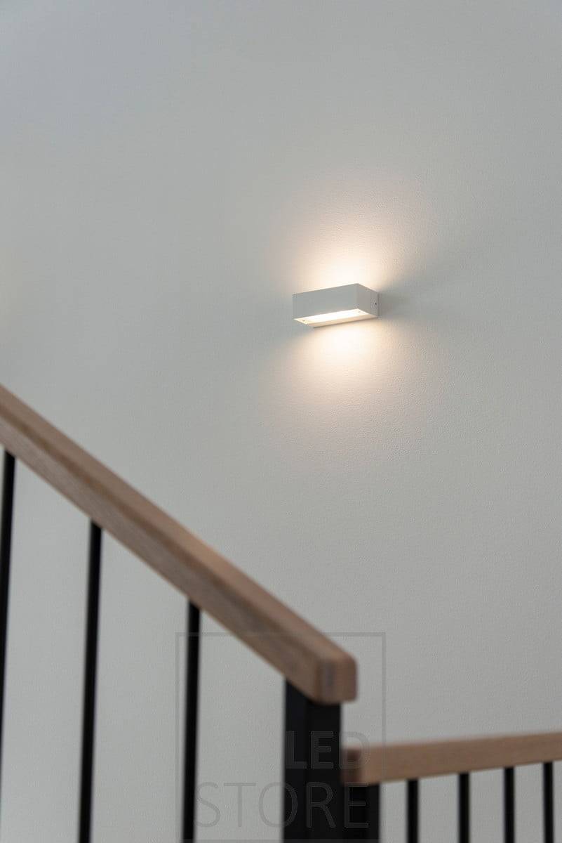 Applique murale bidirectionnelle ANGULAIRE dans un escalier. Elle éclaire le verre gravé d'une lumière douce et atmosphérique. Ledstore.fi