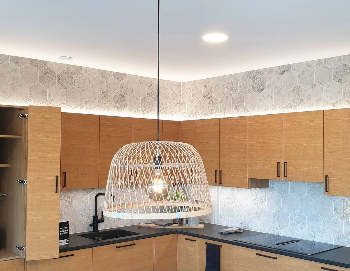 Housing Fair 2020 : lumières indirectes dans le placard de la cuisine sur le dessus de la cuisine en chêne. Plafonds au plafond et lampe suspendue au-dessus de la table à manger. Ledstore.fi