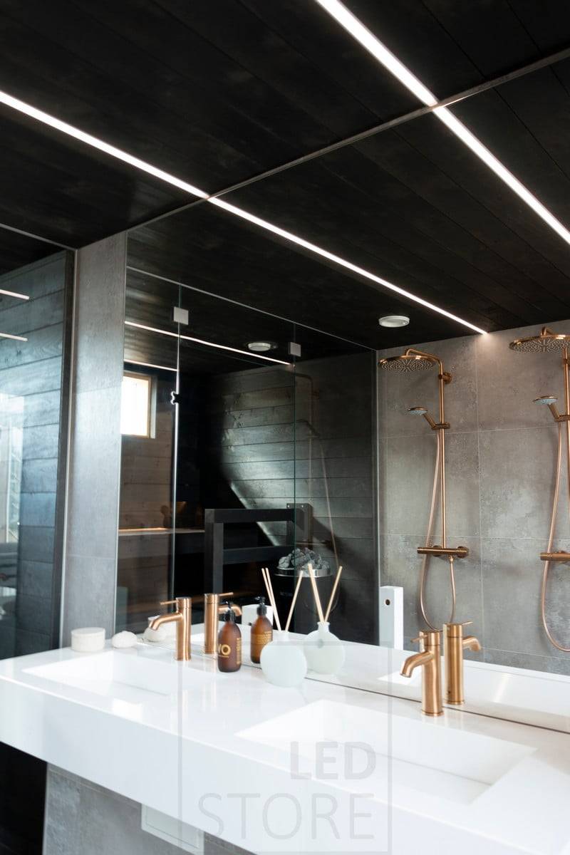 Salon du logement 2020 : des bandes de LED éclairent la salle de bain dans des profils encastrés étroits dans le plafond noir de la salle de bain. L'éclairage crée de belles lignes de lumière dans le plafond. Ledstore.fi