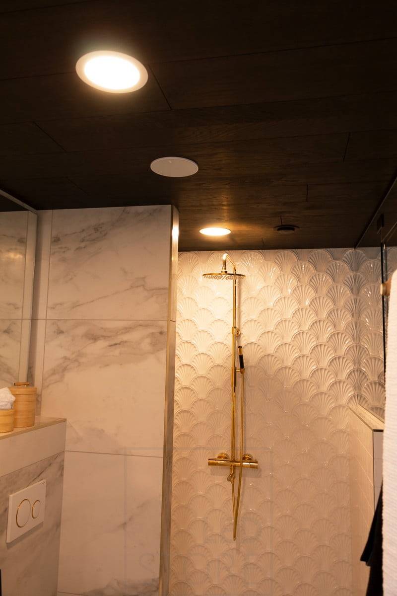 Housing Fair 2020 : plafond dans le plafond de la douche. Notez le reflet de la lumière sur le pommeau de douche. Ledstore.fi