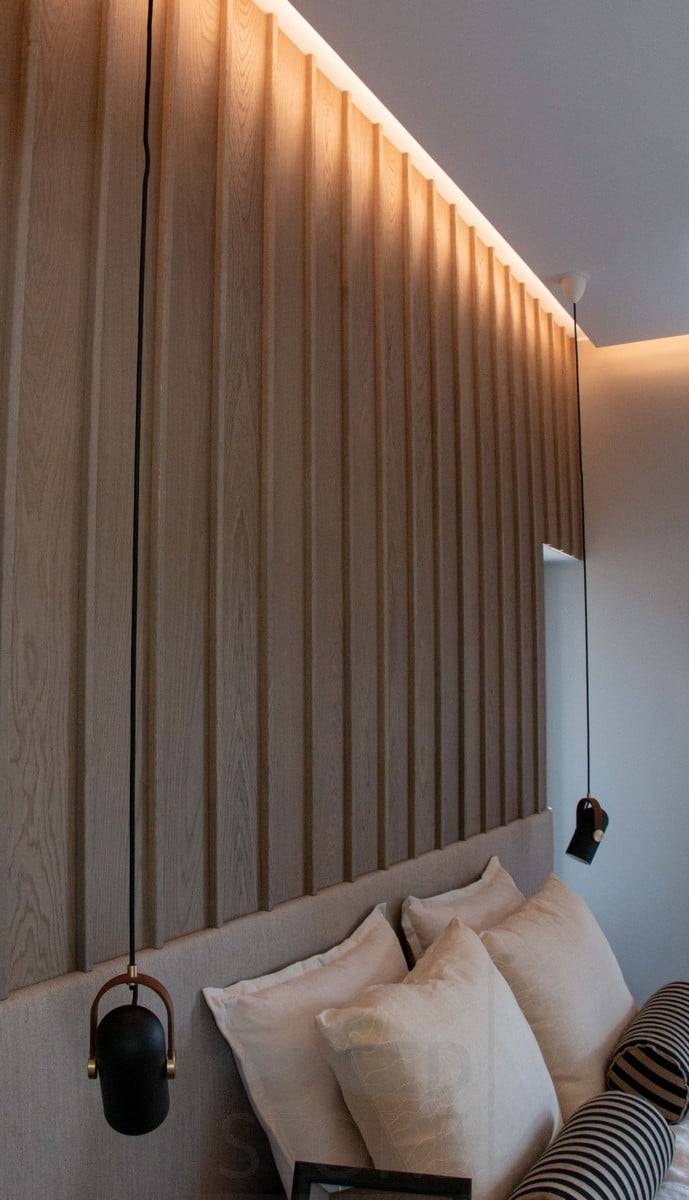 Housing Fair 2022 : Une chambre à coucher avec un éclairage sombre et magnifique créé avec une lumière indirecte. A l'étage inférieur, des luminaires suspendus de part et d'autre du lit. Ledstore.fi