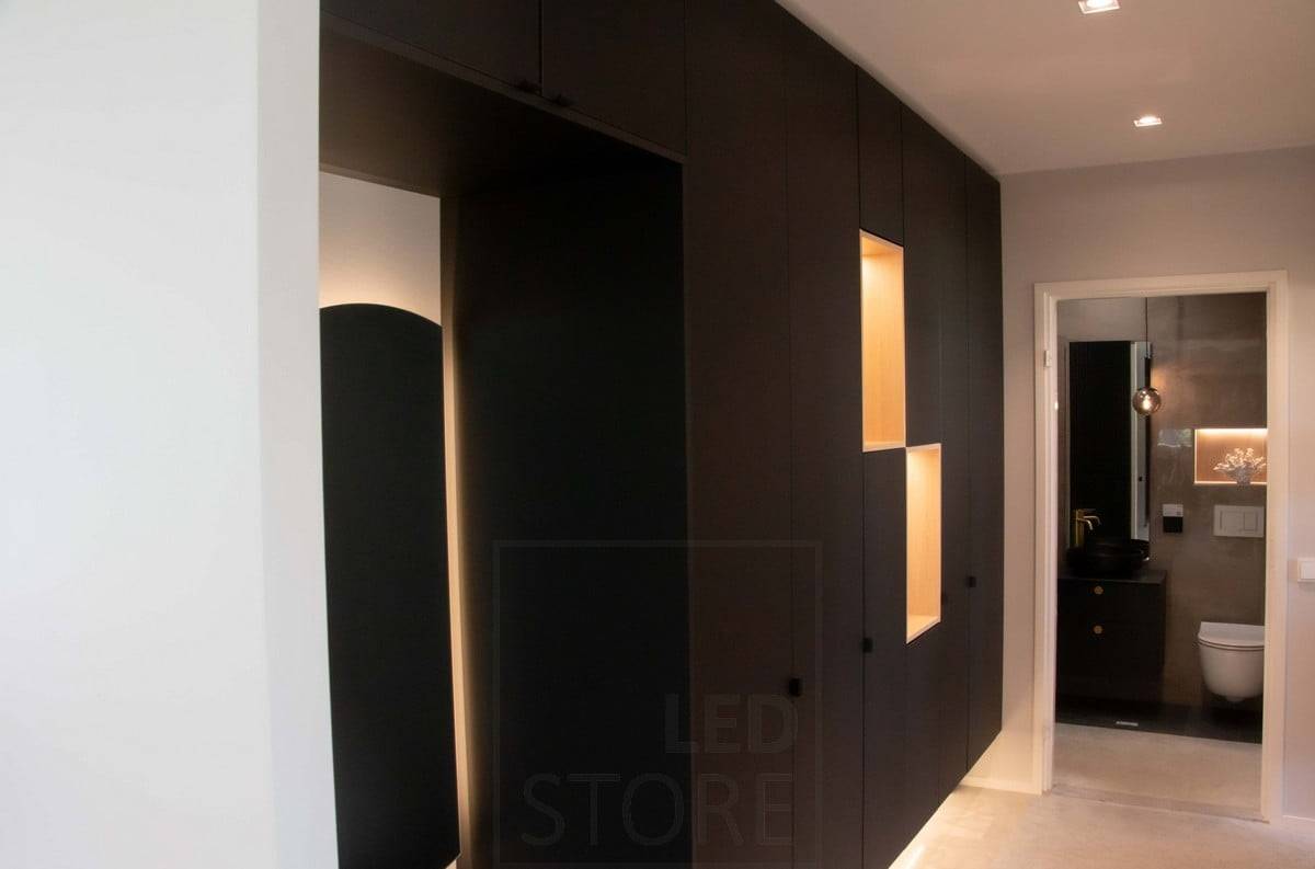Salon du logement 2022 : Des bandes lumineuses à Led sur la plinthe et l'étagère ouverte éclairent la lumière indirecte des armoires du couloir. Ledstore.fi