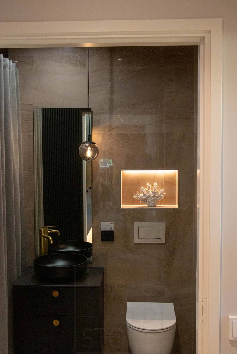 Salon du logement 2022 : Une étagère dans les toilettes, encastrée dans le mur, est équipée d'une bande LED pour mettre en valeur le détail. Une lampe suspendue comme élément décoratif d'ambiance. Ledstore.fi
