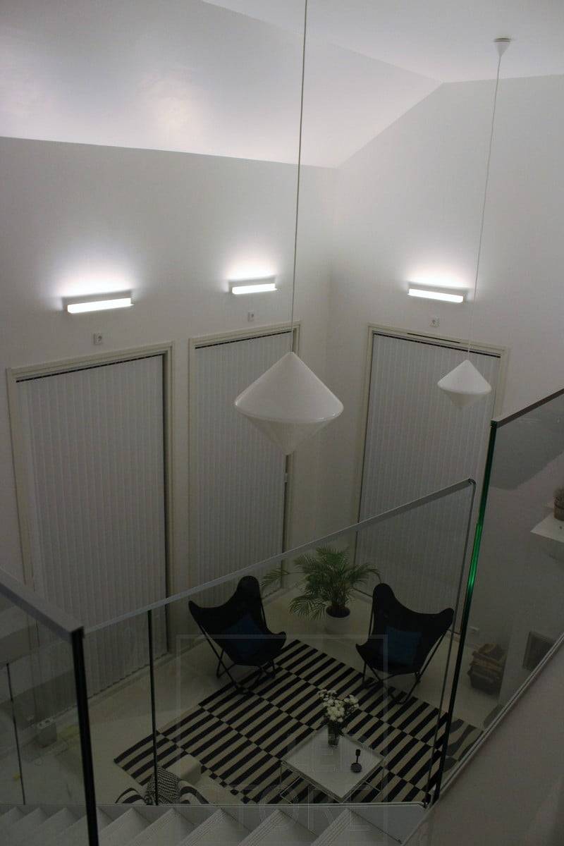 Un salon avec un éclairage indirect atmosphérique créé avec des appliques Led BLADE. Le luminaire est monté de manière à éclairer du bas vers le haut, ce qui permet à l'éclairage indirect de souligner la hauteur de l'espace. Ledstore.fi