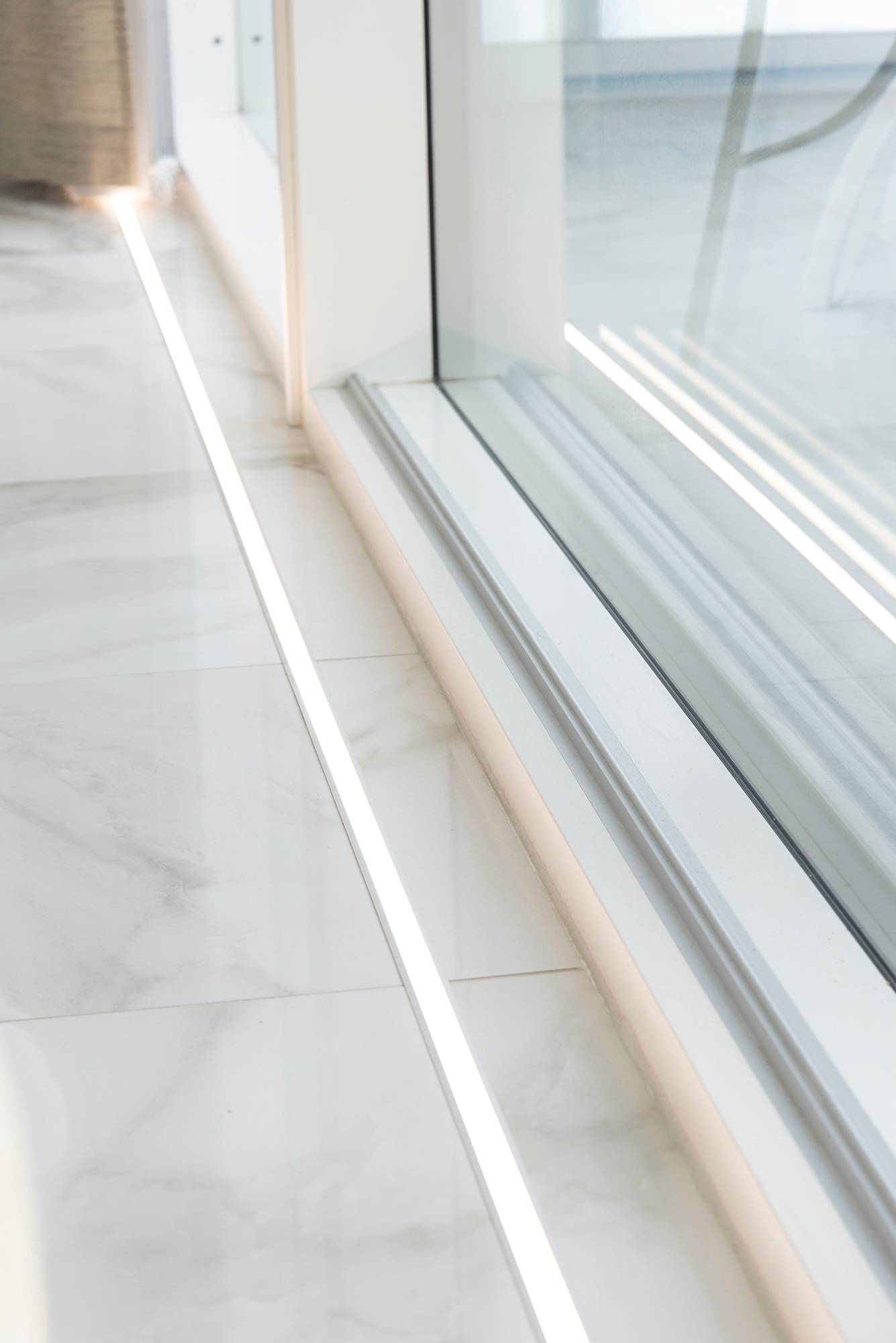 Devant les fenêtres, sur le sol, dans la bande LED uppoprofile. L\'éclairage met en valeur les grandes fenêtres et le beau sol en marbre. Ledstore.fi