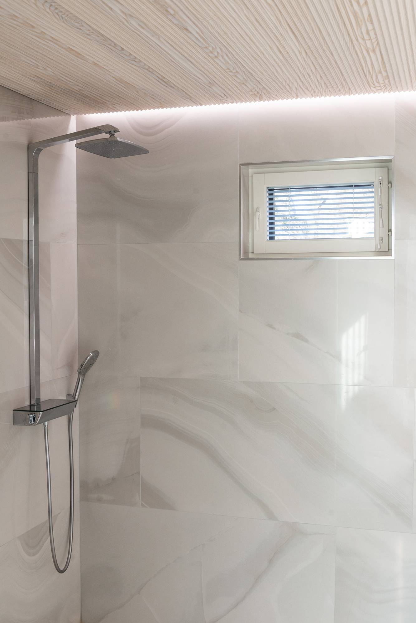 Bande LED entre le plafond et le mur éclairant indirectement la douche, créant une atmosphère de spa. Ledstore.fi