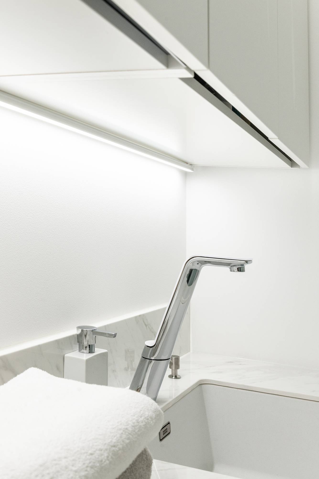 Dans la buanderie, dans l\'angle de l\'armoire et du mur, dans un profil de surface élevé, une bande de LED apporte de la lumière au niveau. Ledstore.fi