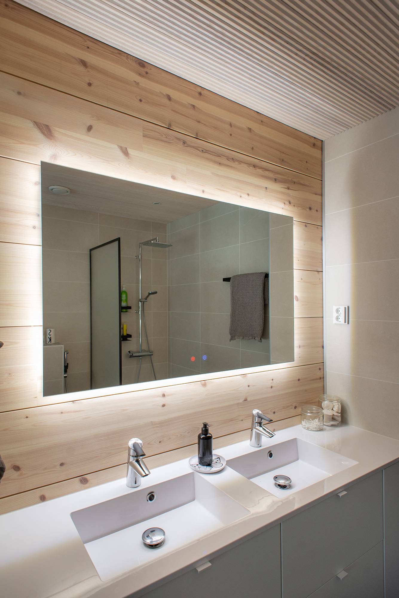 Dans la salle de bains, la lumière provenant de l\'arrière d\'un miroir lumineux de 1200 mm x 750 mm met en valeur les belles boiseries et éclaire le niveau. Ledstore.fi