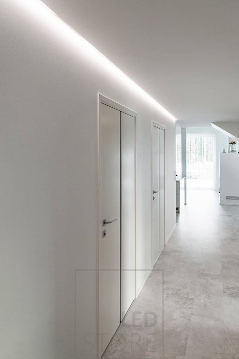 Un couloir magnifiquement éclairé par une lumière indirecte. Bande LED en profilé d'aluminium montée dans la rainure entre le plafond et le mur. Ledstore.fi