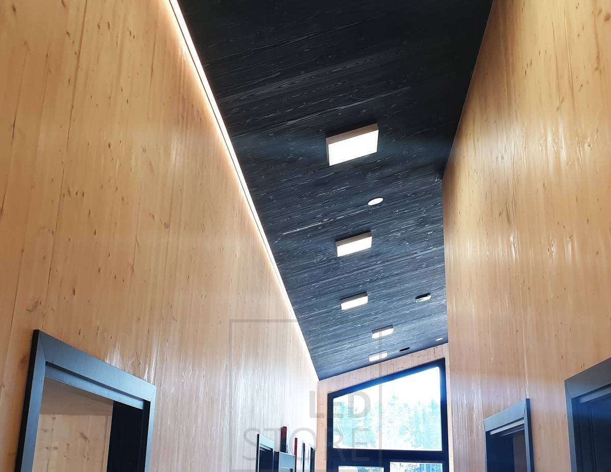 Dans un couloir élevé, une bande LED entre le plafond et le mur fournit un éclairage d'ambiance. Éclairage général avec des panneaux lumineux. Ledstore.fi