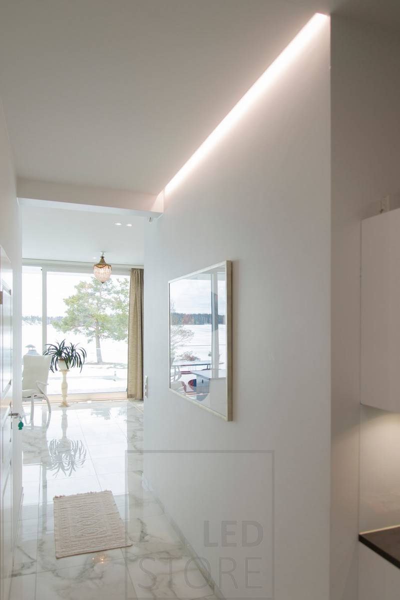 Éclairage indirect dans un couloir avec une bande de LED qui met également en valeur l'œuvre d'art sur le mur. Ledstore.fi