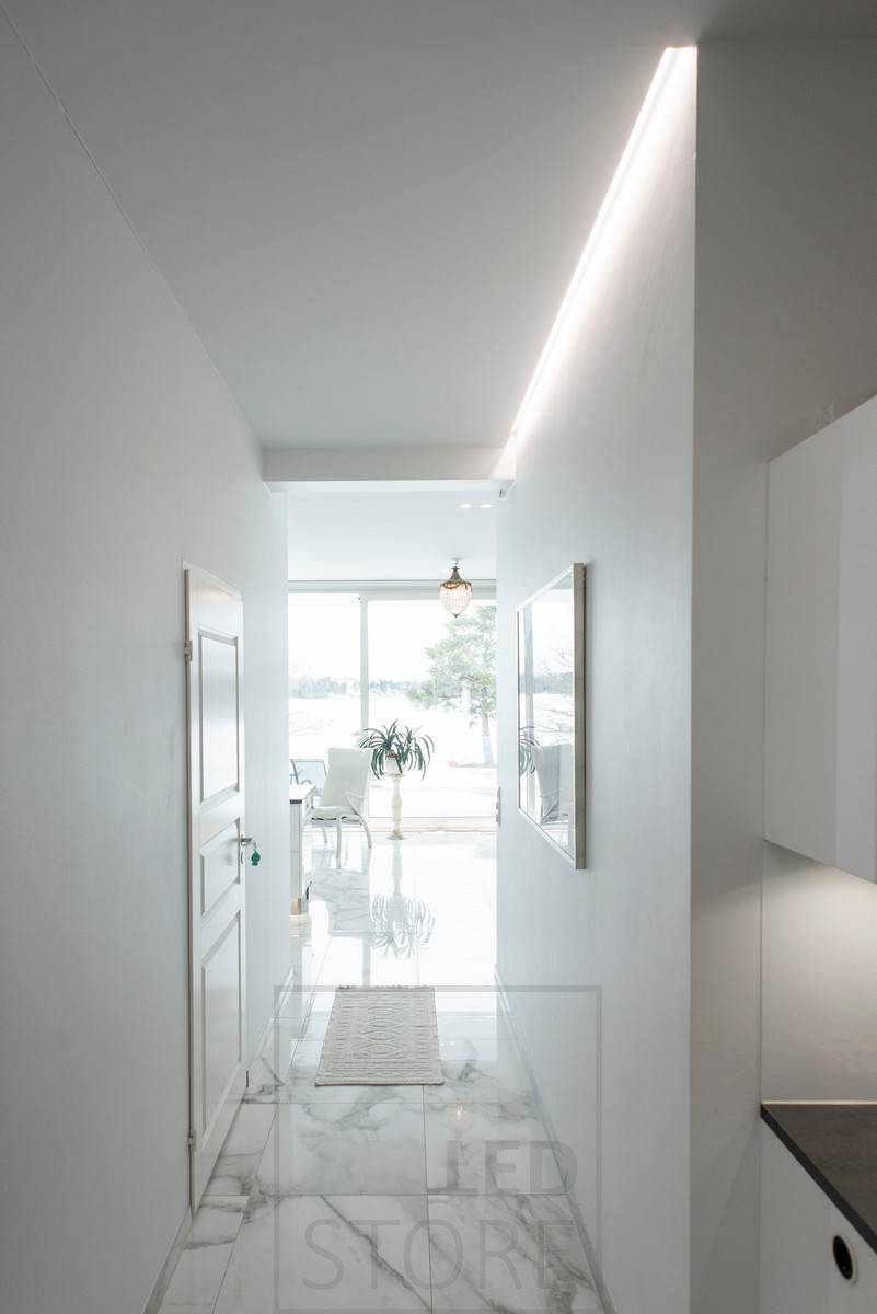 Couloir éclairé par une lumière indirecte, bande LED montée dans une rainure entre le plafond et le mur dans un profilé d'aluminium. Ledstore.fi