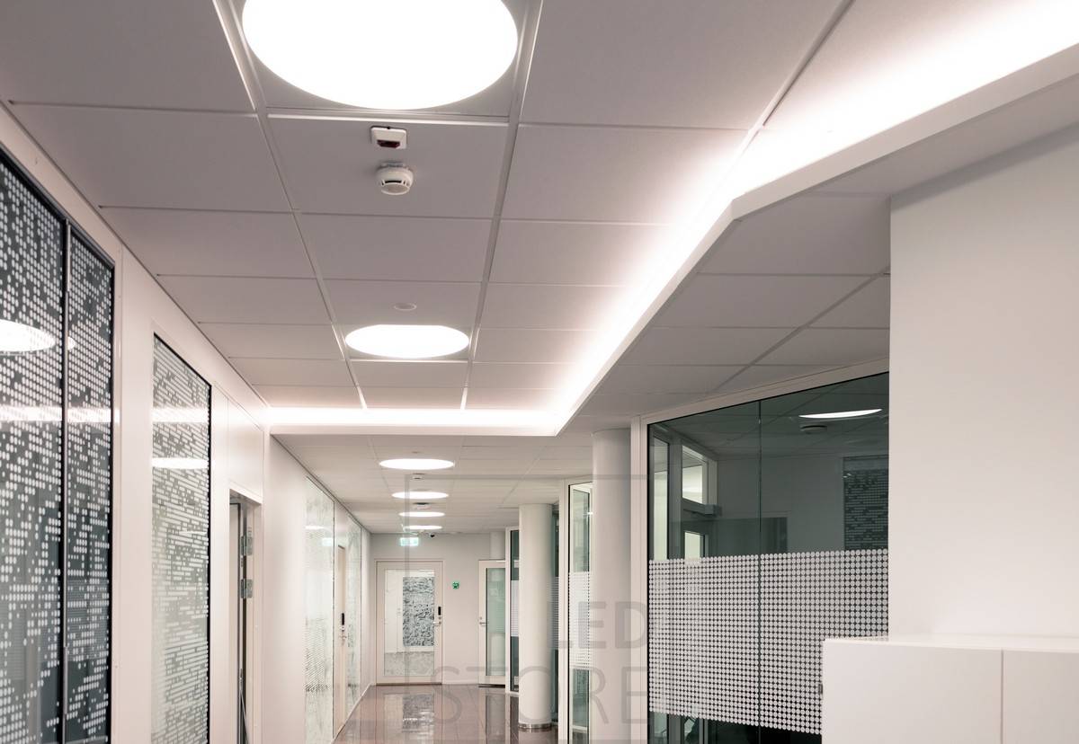Bande LED installée dans le couloir d'un boîtier d'éclairage vers le bas créant une lumière indirecte atmosphérique. L'éclairage général est assuré par des luminaires encastrés Plafondi.