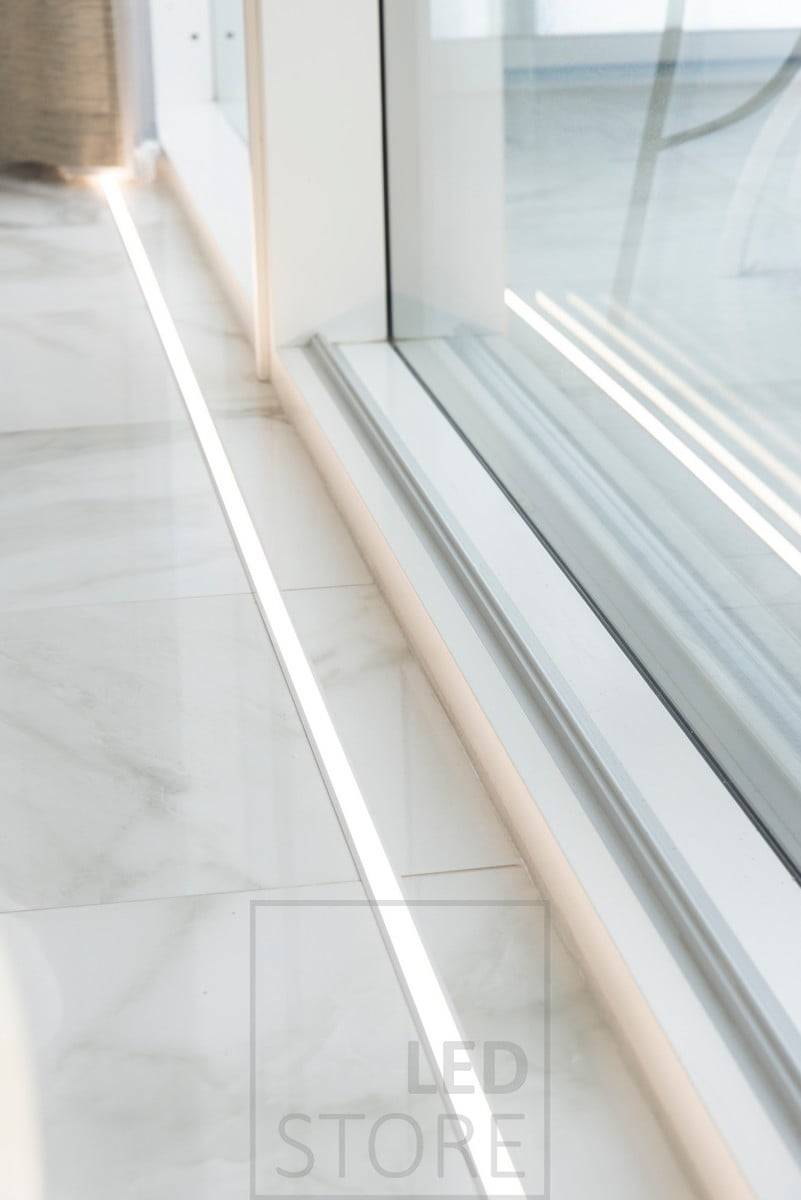 Devant des fenêtres allant du sol au plafond, une bande LED dans un profilé encastré. L'uplight accentue les fenêtres et met en valeur le magnifique sol en marbre. Ledstore.fi