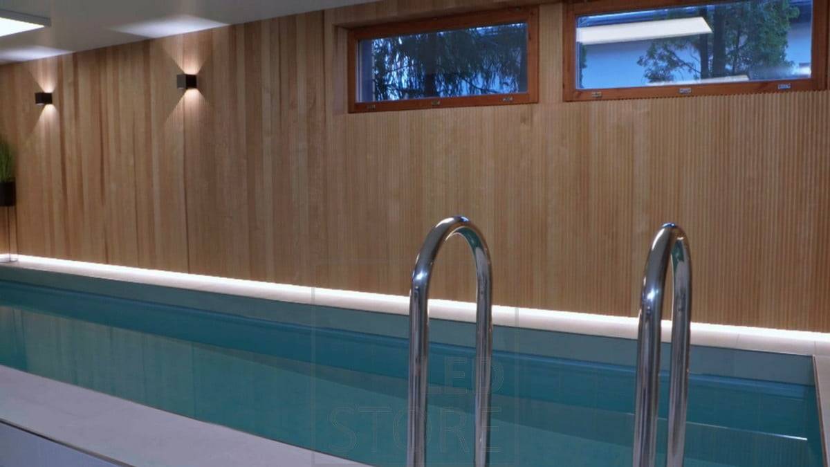 L'espace piscine est éclairé par des appliques FUNK et, derrière les magnifiques lambris, la bordure du sol est éclairée par la lumière indirecte des bandes LED. Ledstore.fi
