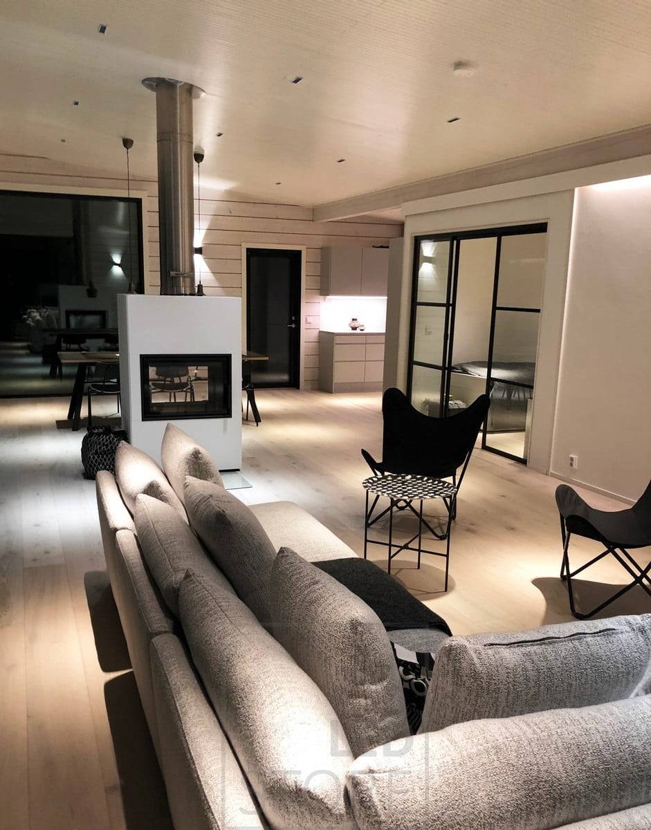 L'applique FUNK noire éclaire le salon et la salle à manger d'une lumière d'ambiance à travers le mur. Les petits spots LINJA2 assurent l'éclairage général de l'espace. Ledstore.fi