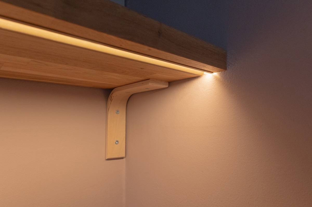 Gros plan d\'un profilé encastré dans le fond d\'une étagère. La couleur du profilé est un cuivre mat.