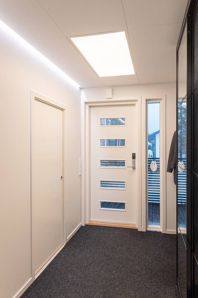 Le hall d'entrée lumineux est éclairé par un grand panneau et une bande de LED.