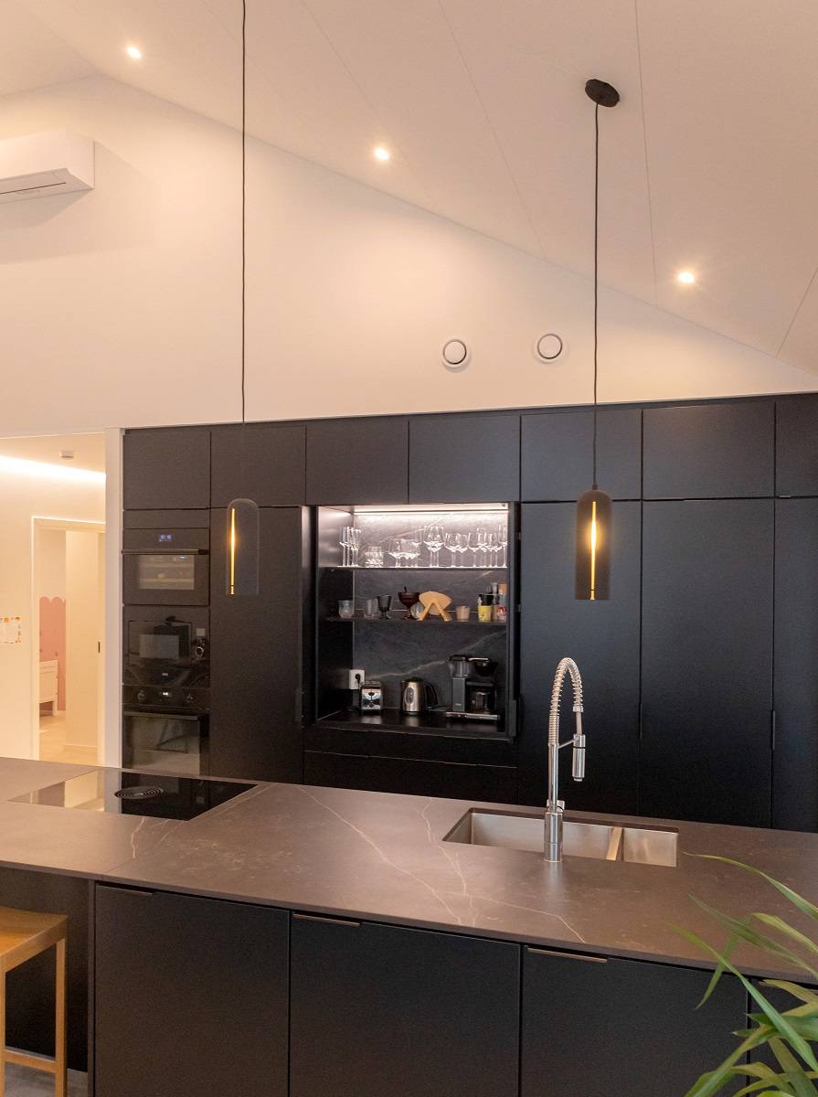 Meuble de petit-déjeuner avec bandeau lumineux LED et spots sur le plafond incliné de la cuisine.