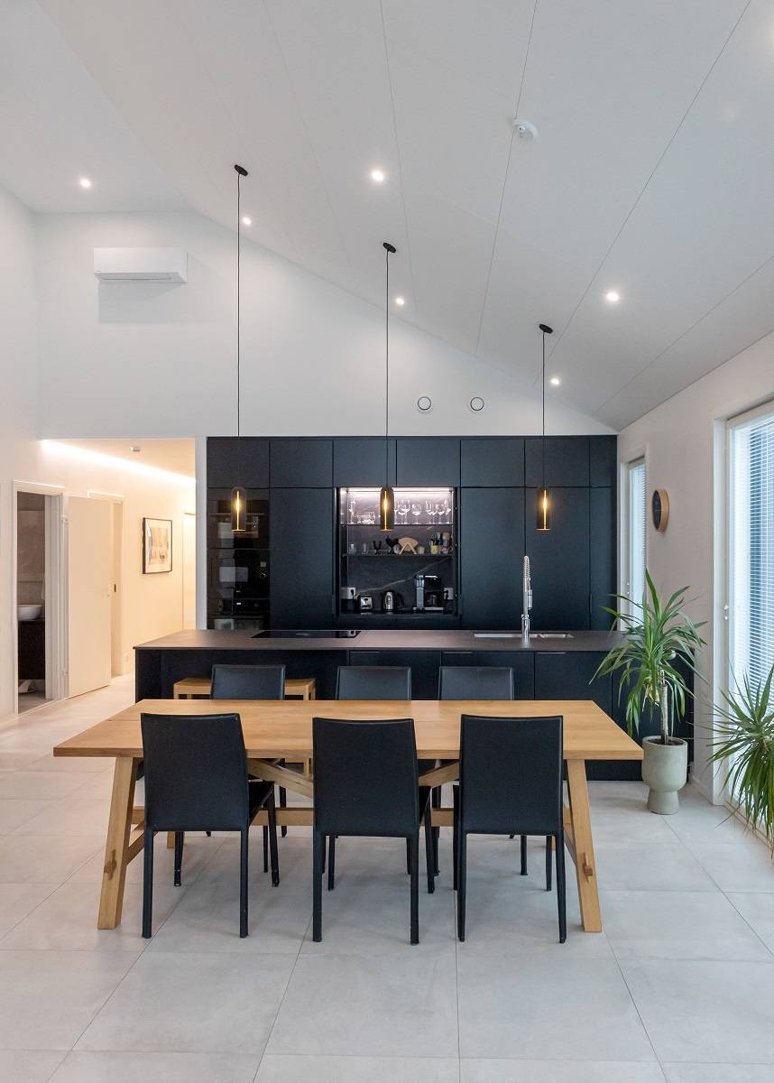 Le plafond de la cuisine est équipé de spots pour l'éclairage général, le meuble du petit déjeuner est équipé d'une bande de LED et de lampes suspendues au-dessus du niveau.