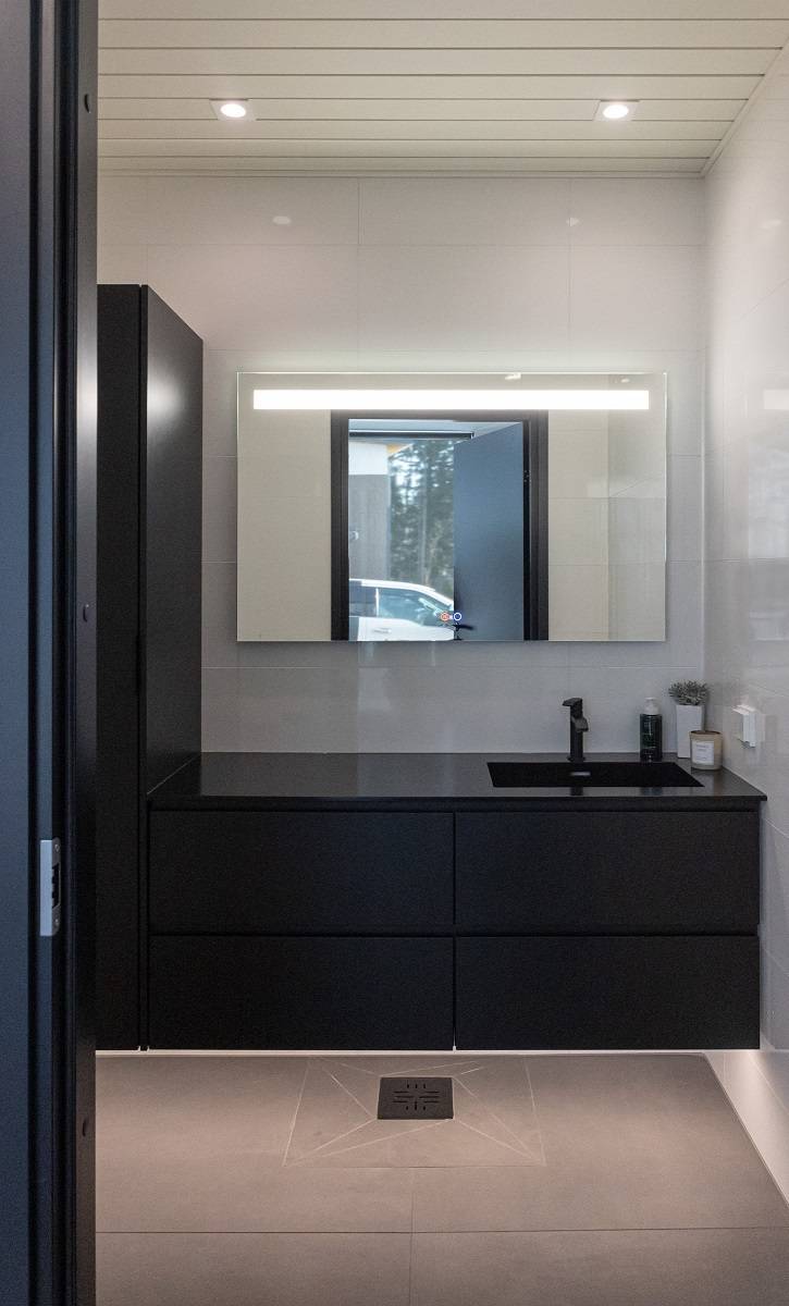 Salle de bains avec bande LED sous les armoires pour une lumière indirecte, miroir SEELIA et deux downlights LED SQ023 au plafond.
