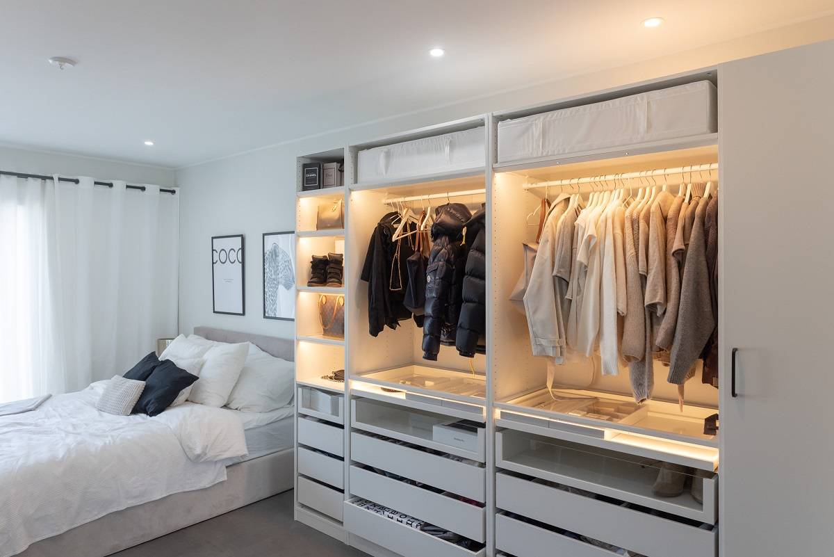 Chambre à coucher avec spots ronds et armoire éclairée par une bande LED.