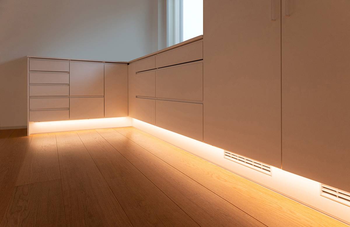 Une lampe placée dans le socle de la cuisine qui éclaire le sol.