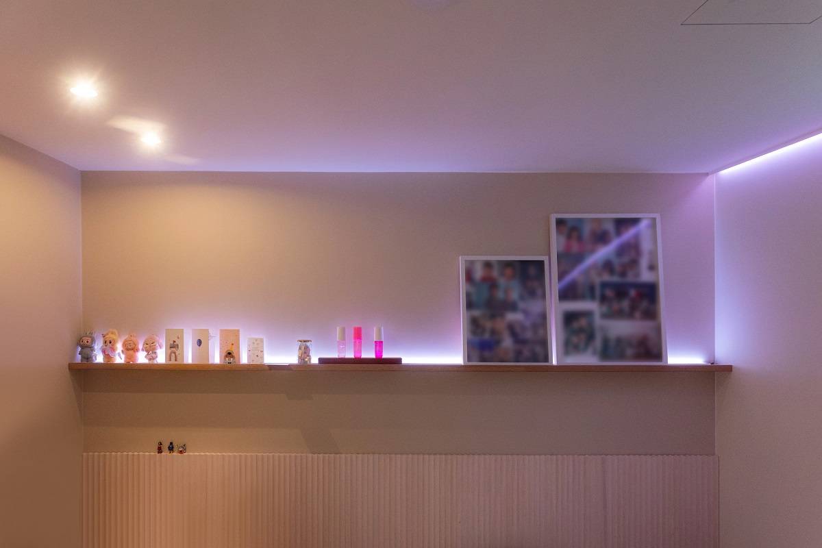 Une bande LED diffusant une lumière violette fait le tour de la pièce ; deux spots sont également fixés au plafond.